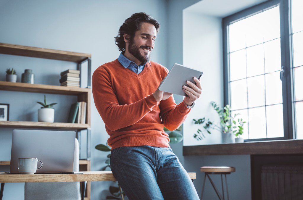 Businessman leaning on the table and working on digital tablet.